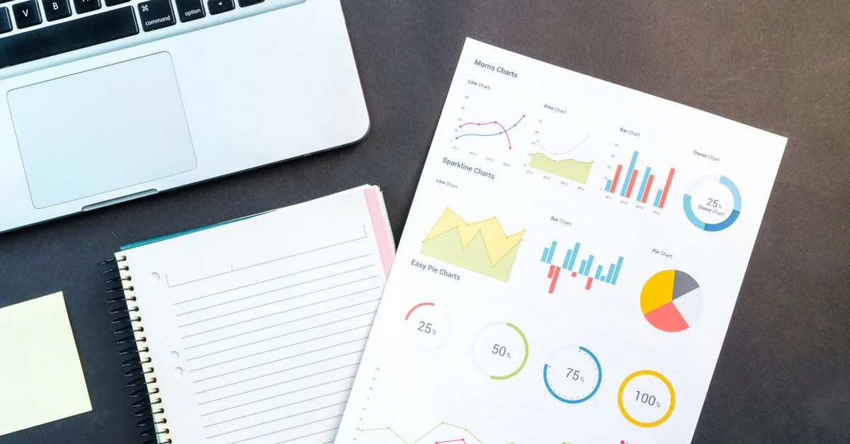 Vue aérienne d'un rapport d'affaires avec des graphiques colorés, un carnet et un ordinateur portable pour l'analyse des données sur un bureau.