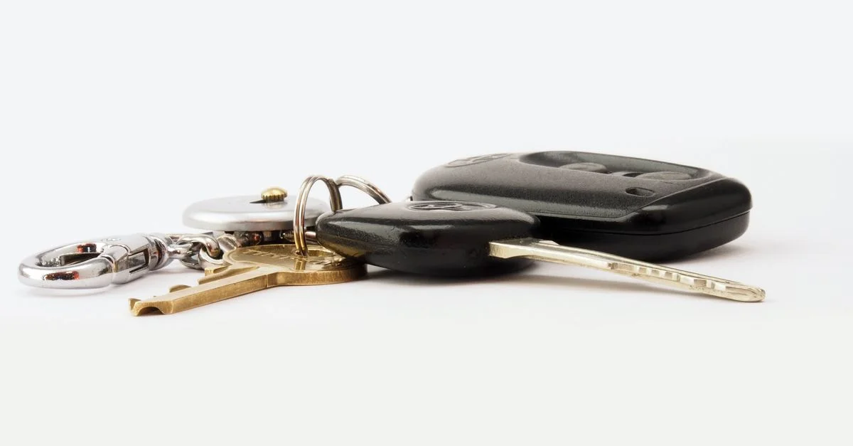 Image détaillée de clés de voiture sur une surface blanche, comprenant un porte-clé et un porte-clés.