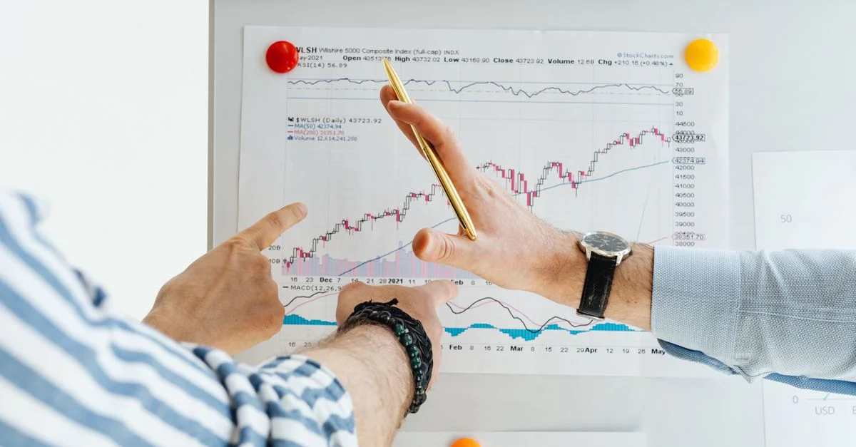 Des professionnels analysent des graphiques financiers lors d'une réunion au tableau blanc.