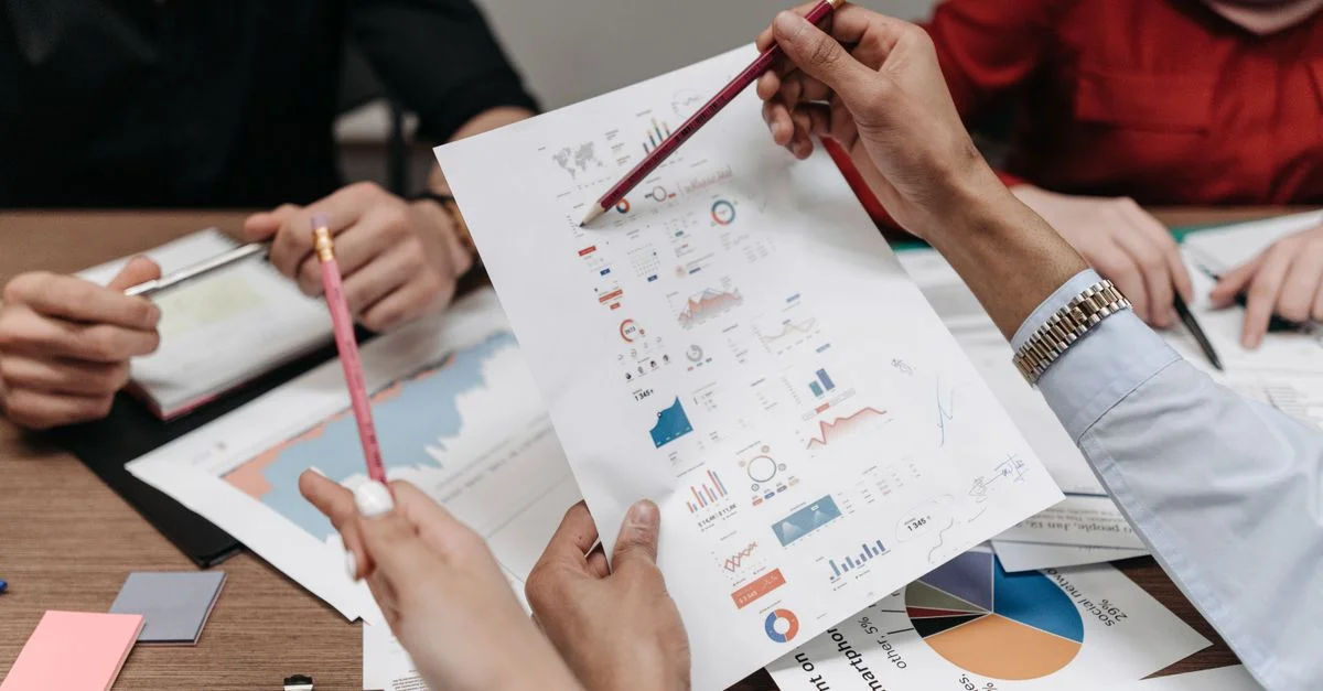 Équipe analysant des rapports d'affaires et des graphiques lors d'une réunion collaborative.