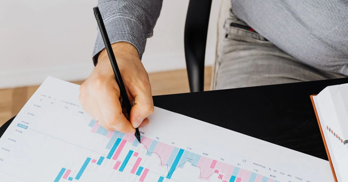 Graphique financier détaillé montrant l'analyse par une personne avec un stylo à l'intérieur.