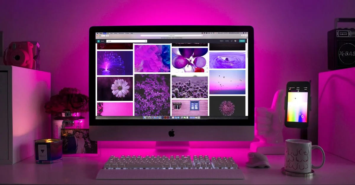 Bureau moderne avec éclairage néon et un ordinateur de bureau affichant des images colorées.