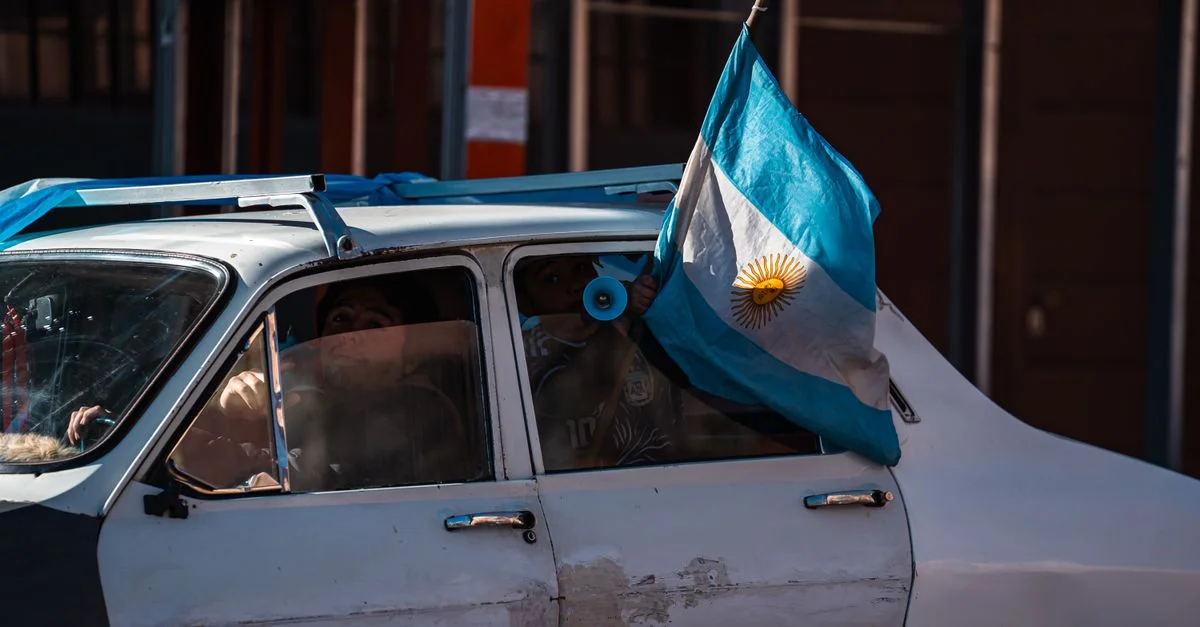 Une vieille voiture en ville arbore le drapeau argentin, symbolisant la fierté nationale.