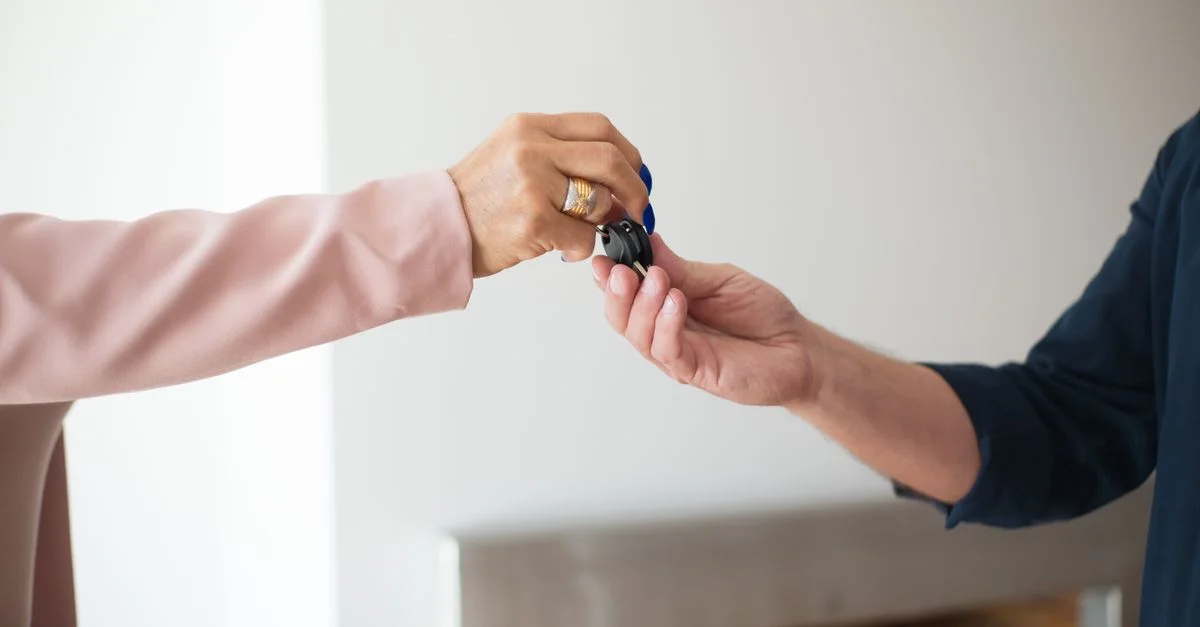 Une photo en gros plan illustrant l'échange de clés entre deux adultes, symbole d'une transaction immobilière.