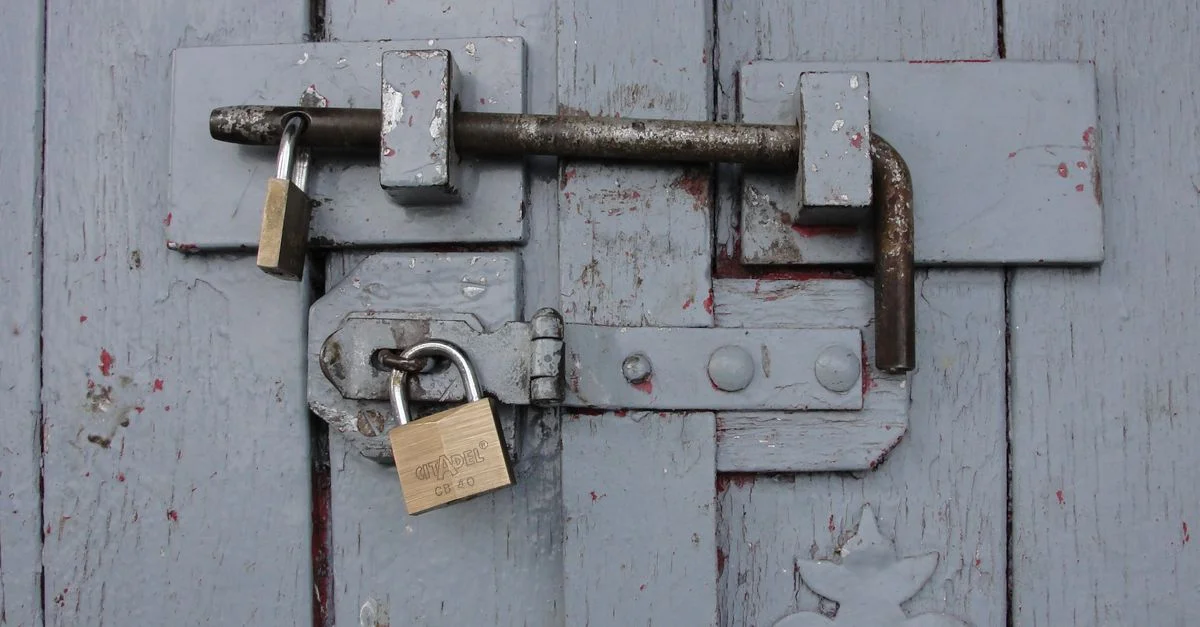Vue détaillée d'une porte en bois solidement verrouillée avec des cadenas en laiton patinés.