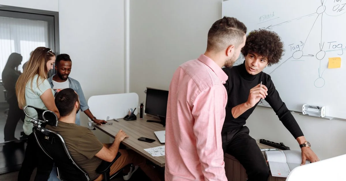 Équipe diverse engagée dans une discussion productive au bureau, échangeant des idées sur un projet.