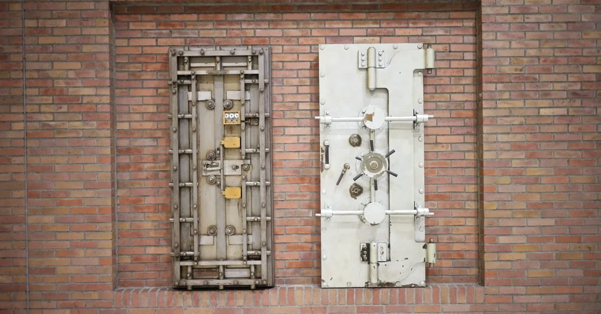 Deux portes de coffre-fort en acier sécurisées, fixées à un mur en briques vintage, montrant une force industrielle.