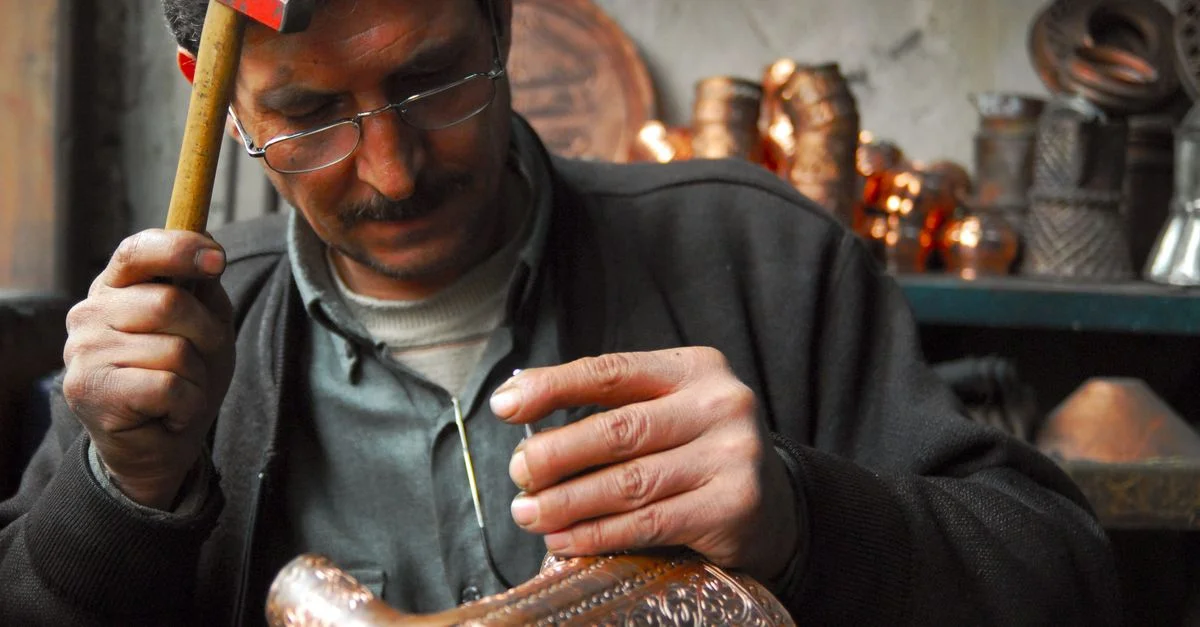 Artisan habile se concentre sur la création d'objets en cuivre complexes avec un marteau dans un atelier.