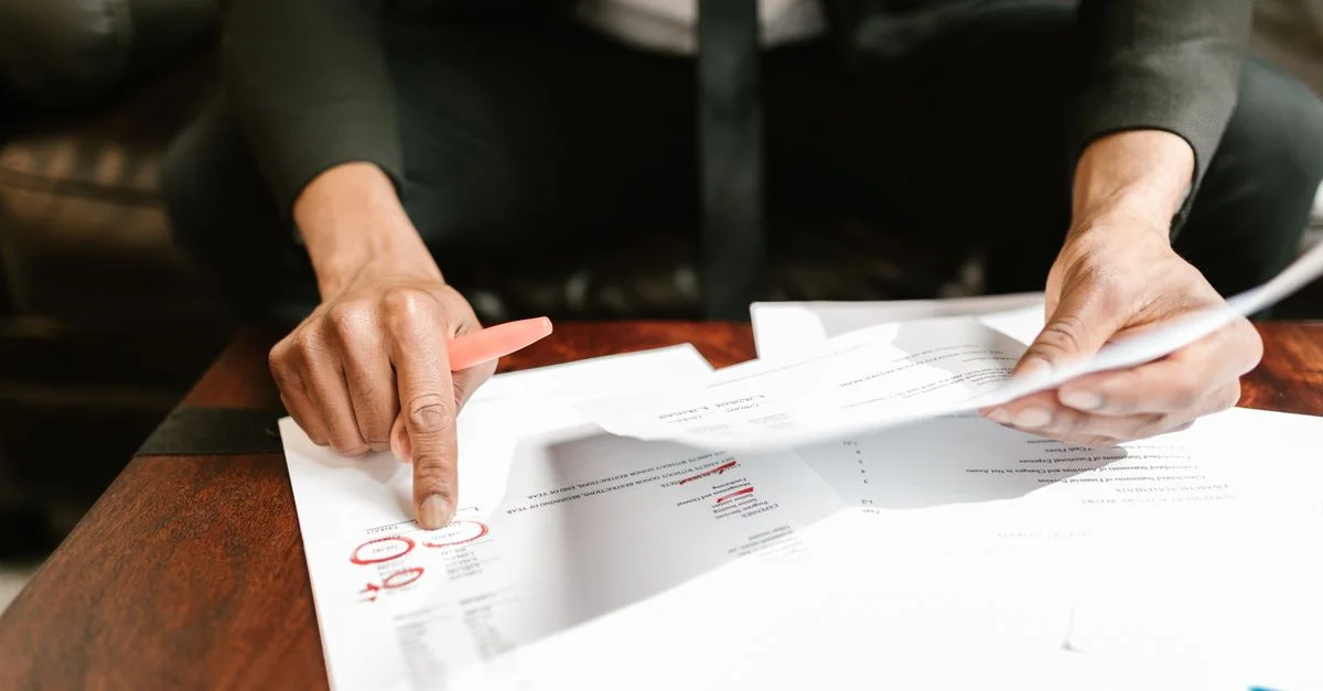 Un homme d'affaires analysant des documents financiers avec des données et des chiffres importants sur un bureau, idéal pour des thèmes d'analyse commerciale et de comptabilité.