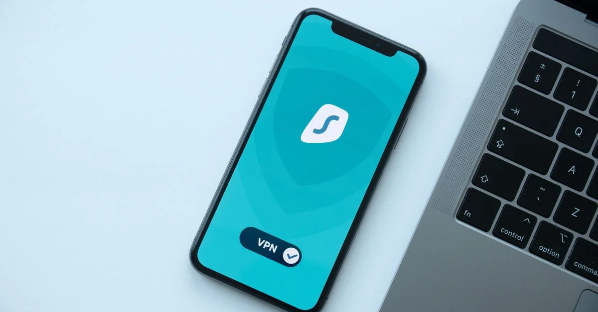 Vue de dessus d'un smartphone affichant une application VPN à côté d'un ordinateur portable sur un bureau.