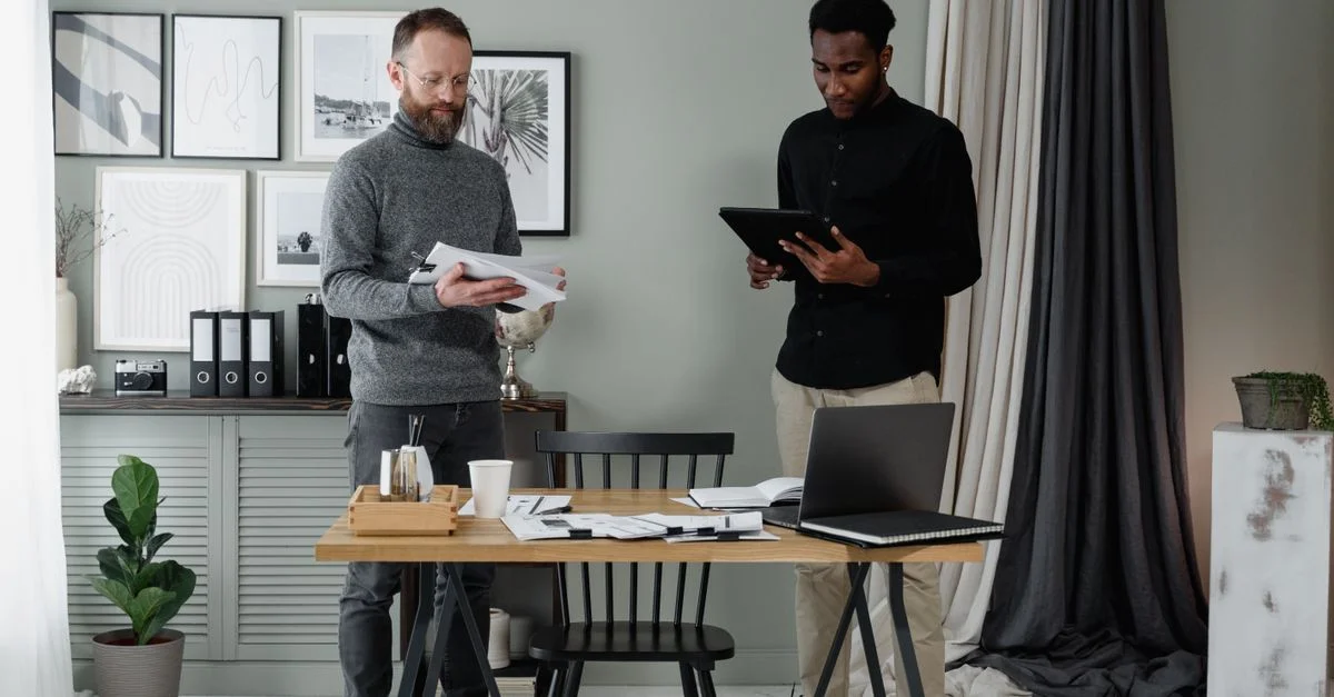Deux professionnels discutant de documents dans un environnement de bureau moderne et élégant.