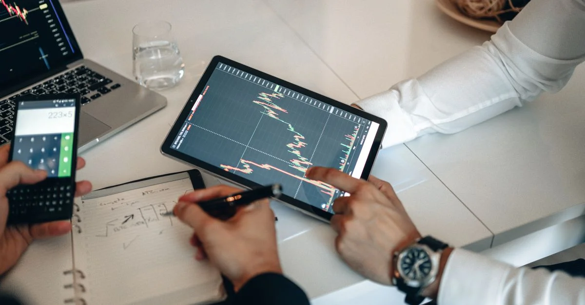Équipe travaillant sur une analyse financière utilisant une tablette et une calculatrice au bureau.