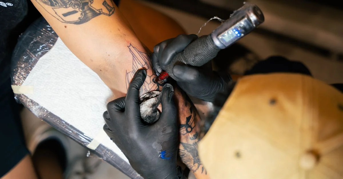 Un tatoueur réalise un motif complexe sur le bras du client avec précision et soin.