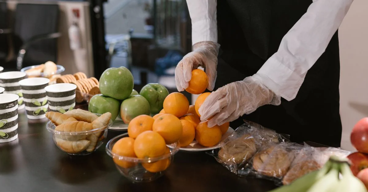Traiteur disposant des fruits frais et des collations sur une table pour un événement de restauration.