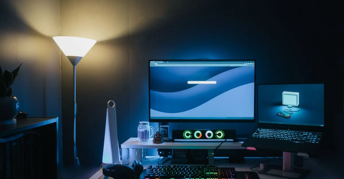 Un bureau à domicile élégant avec un double écran et un éclairage ambiant bleu.