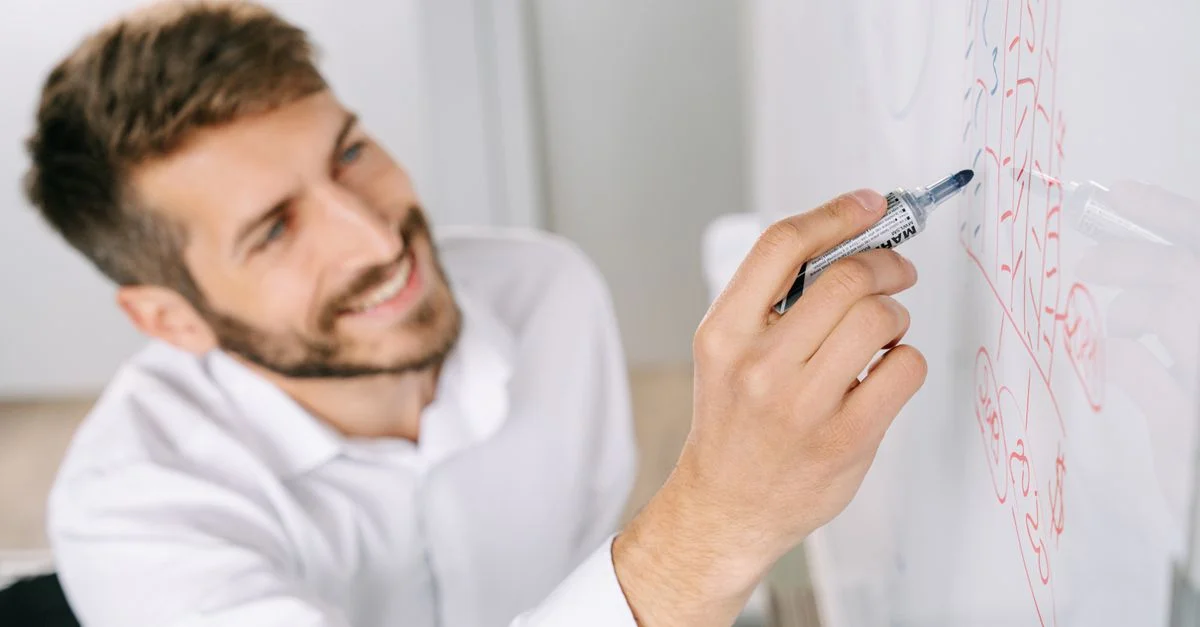 Un homme professionnel écrivant des idées sur un tableau blanc dans un cadre de bureau moderne.