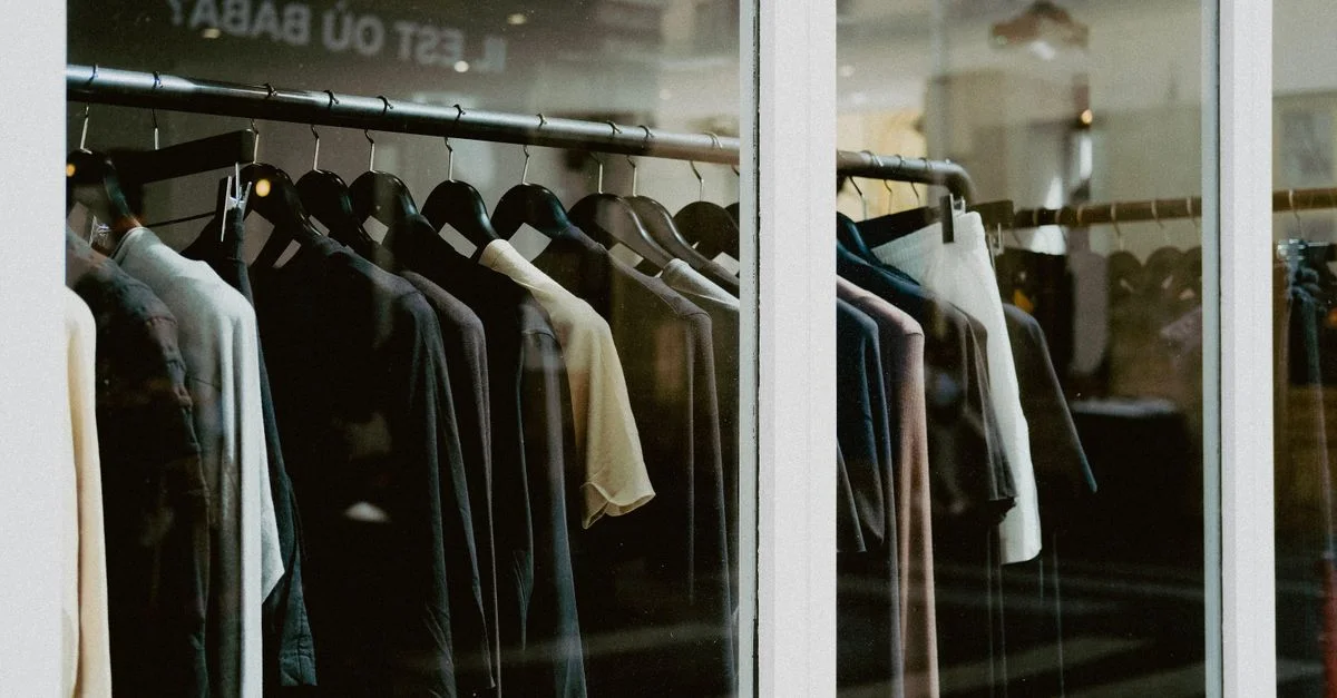 Gros plan sur des vêtements sur cintres à l'intérieur d'une vitrine de magasin de mode.