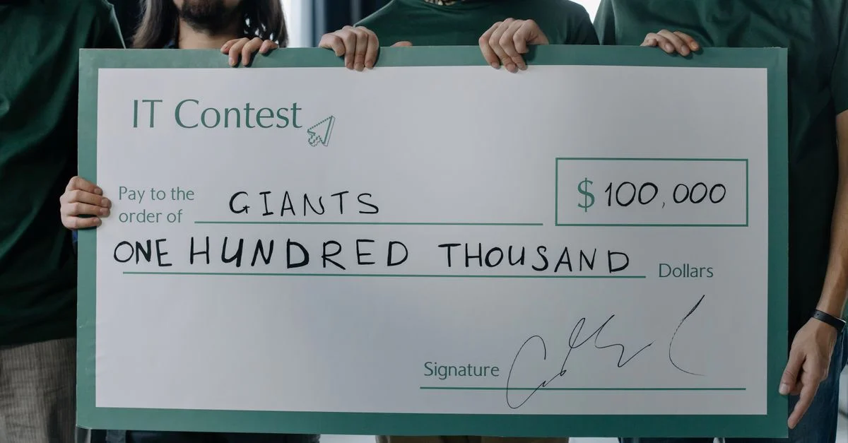 Groupe d'hommes tenant un chèque de prix de 100 000 $ après avoir gagné un concours IT.