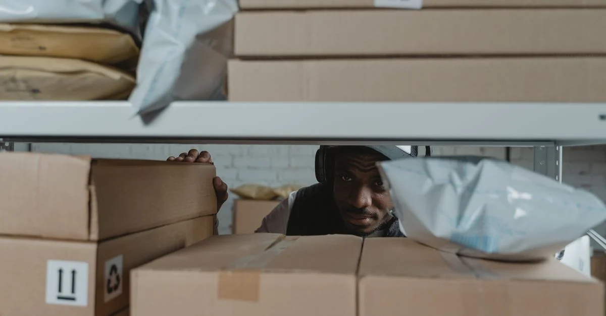 Un employé d'entrepôt inspecte des colis d'expédition sur des étagères, garantissant la qualité et la précision dans la logistique.