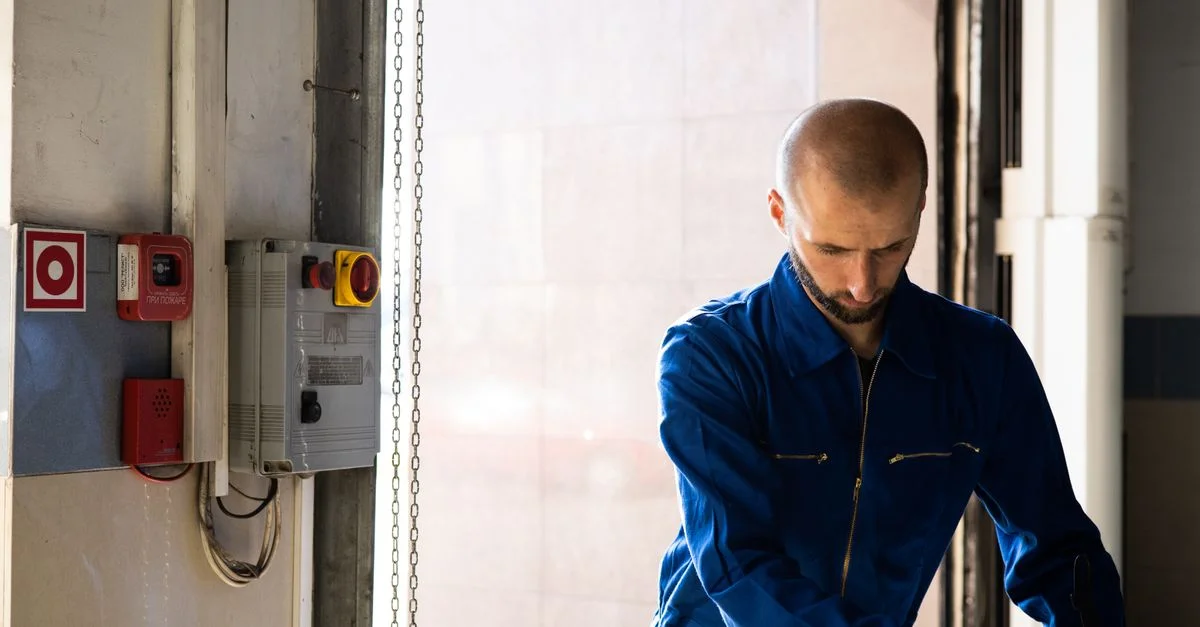 Technicien caucasien travaillant en intérieur avec des EPI dans un environnement industriel.