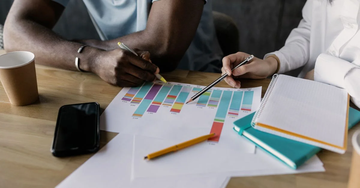 Deux professionnels planifiant une stratégie commerciale à l'aide de graphiques et de documents.