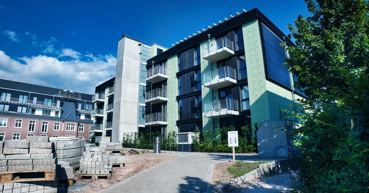 Un immeuble contemporain avec des accents verts et des balcons dans un cadre urbain.