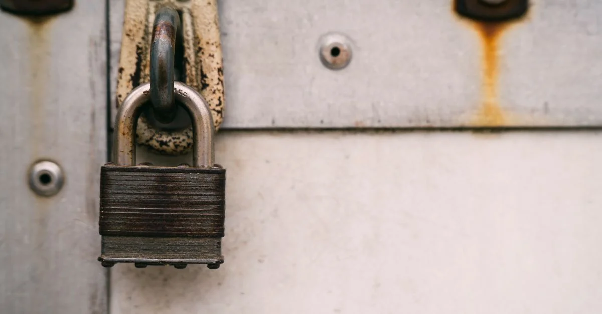 Gros plan d'un cadenas en métal rouillé sur une porte usée, mettant en avant la sécurité et la décomposition.
