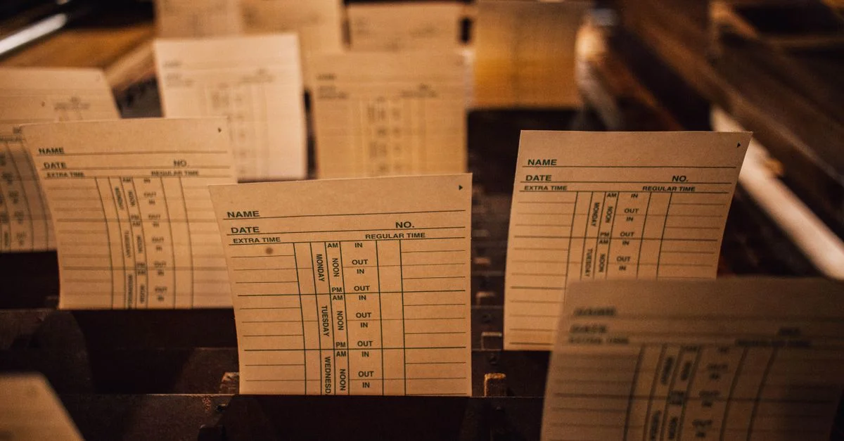 Gros plan sur des cartes de temps vintage dans un système de classement en bois, mettant en avant la documentation de bureau rétro.