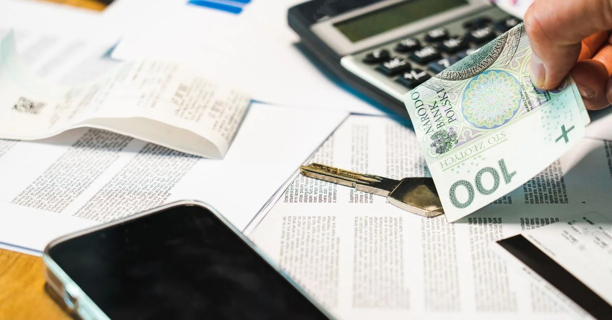 Gros plan sur des documents financiers, une calculatrice et des billets de Zloty polonais sur un bureau.