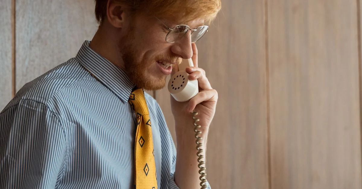 Un homme d'affaires avec des lunettes passe un appel téléphonique dans un cadre de bureau rétro.