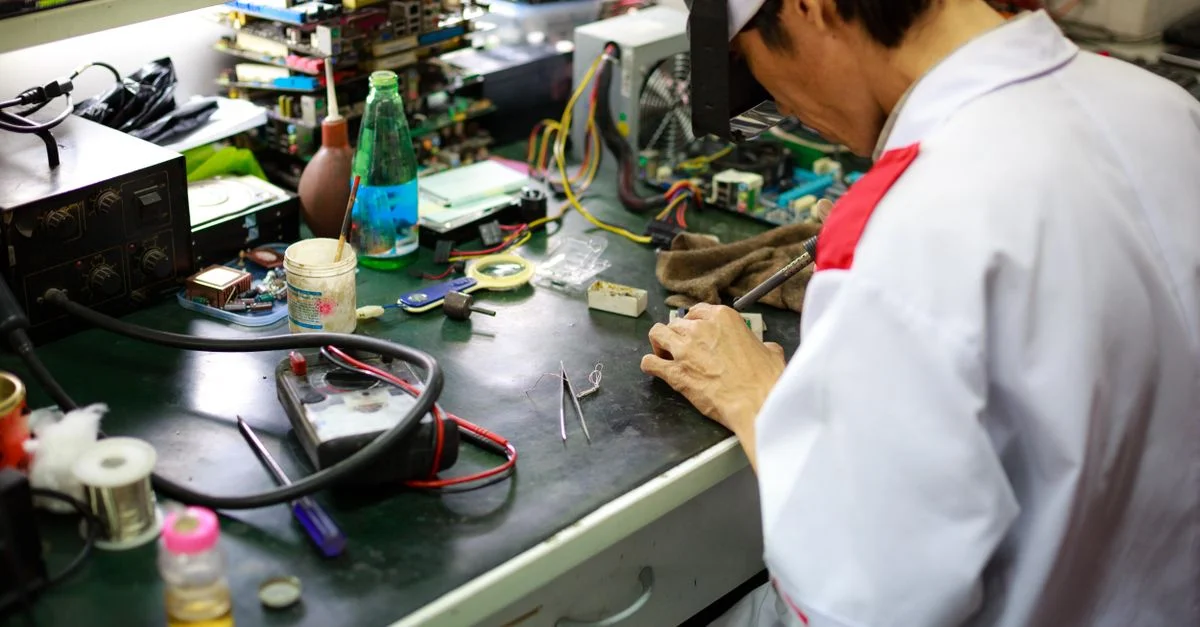 Un technicien qualifié se concentre sur la réparation de composants électroniques sur un établi encombré.