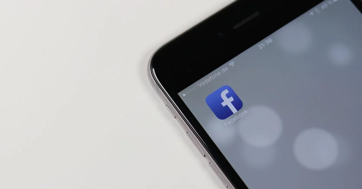 iPhone affichant l'icône de l'application Facebook avec un fond flou, soulignant la connectivité des médias sociaux.