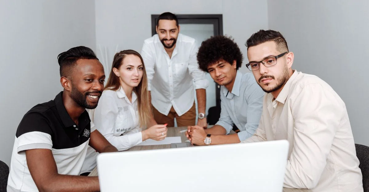 Un groupe diversifié de professionnels participant à une réunion collaborative autour d'un ordinateur portable dans un bureau.