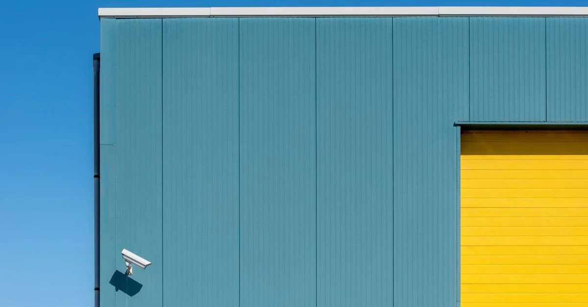 Composition architecturale simple avec une caméra de sécurité sur une façade de bâtiment colorée.