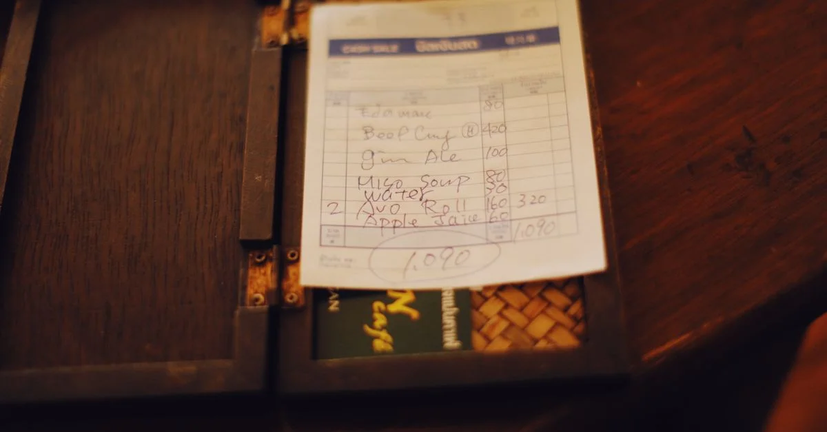 Gros plan sur une note de restaurant placée sur une table en bois foncé, créant une ambiance tamisée.