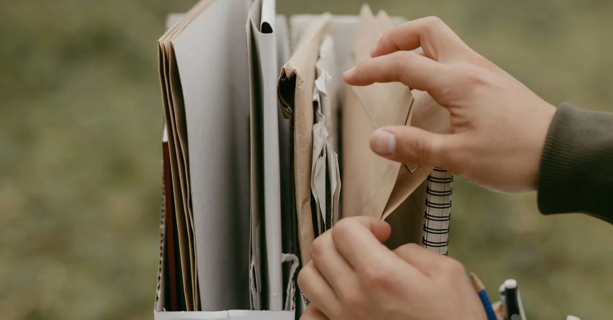Des mains organisant des documents et des enveloppes, mettant en avant le travail de bureau et l'organisation en plein air.