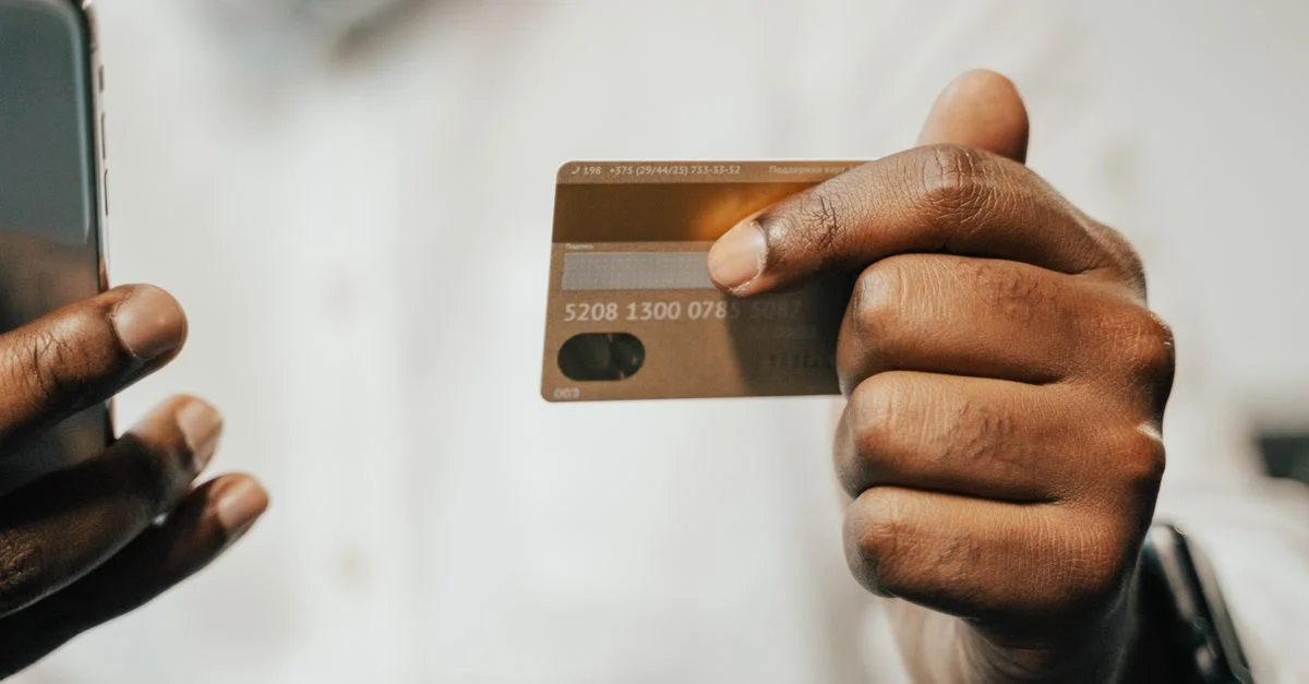 Personne utilisant un smartphone et une carte de crédit pour des achats ou paiements en ligne.