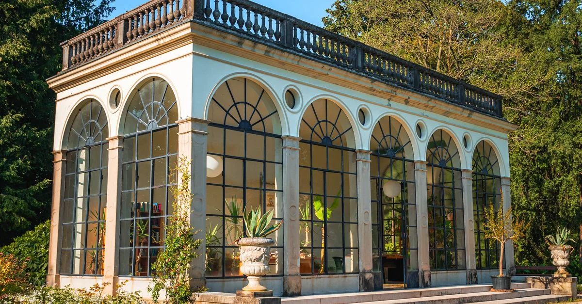 Une véranda de jardin magnifiquement conçue baignée de soleil et entourée d'une verdure luxuriante.