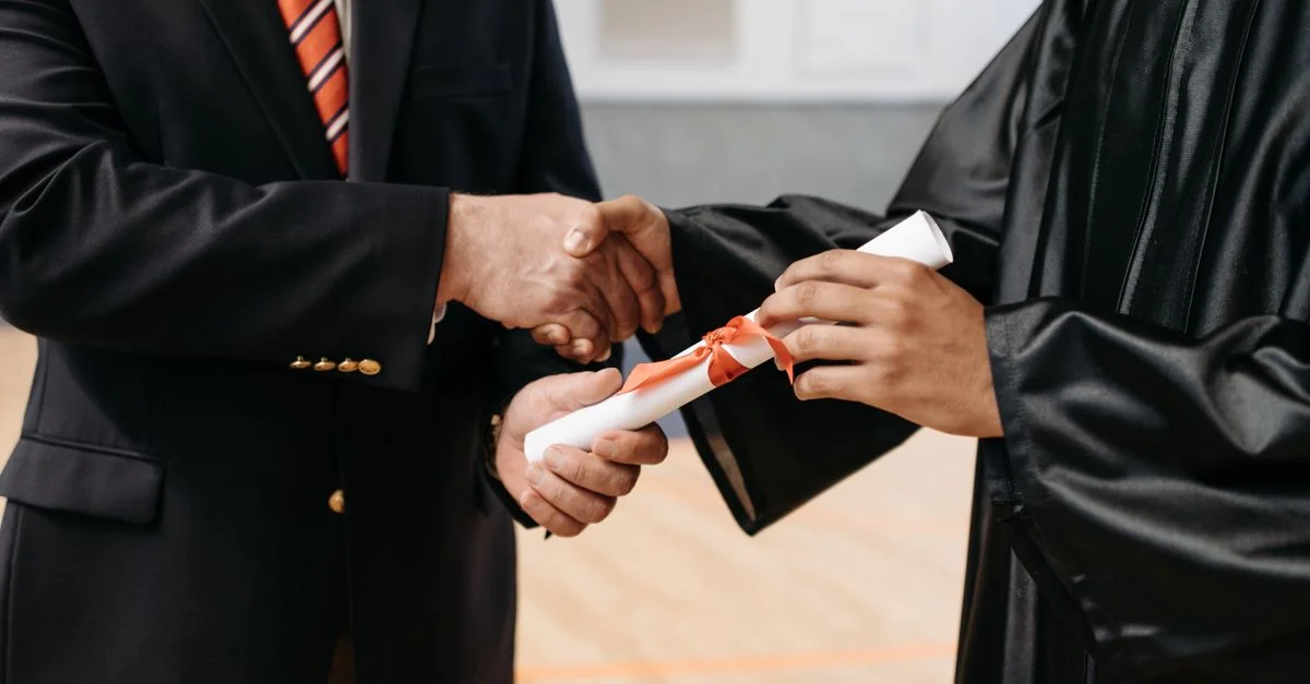 Gros plan sur un diplômé recevant son diplôme lors d'une poignée de main de cérémonie de remise des diplômes.