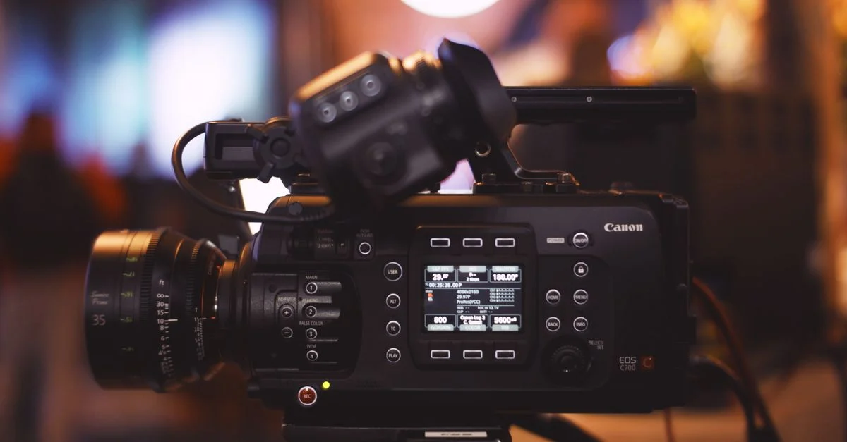 Gros plan sur une caméra vidéo professionnelle dans un environnement de studio, mettant en avant l'objectif et les commandes.