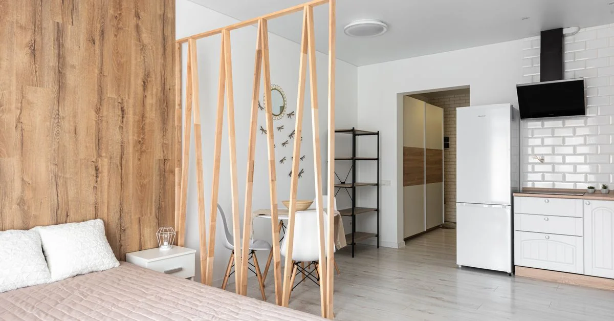 Appartement au design élégant avec une cloison en bois, un lit confortable et une cuisine moderne.