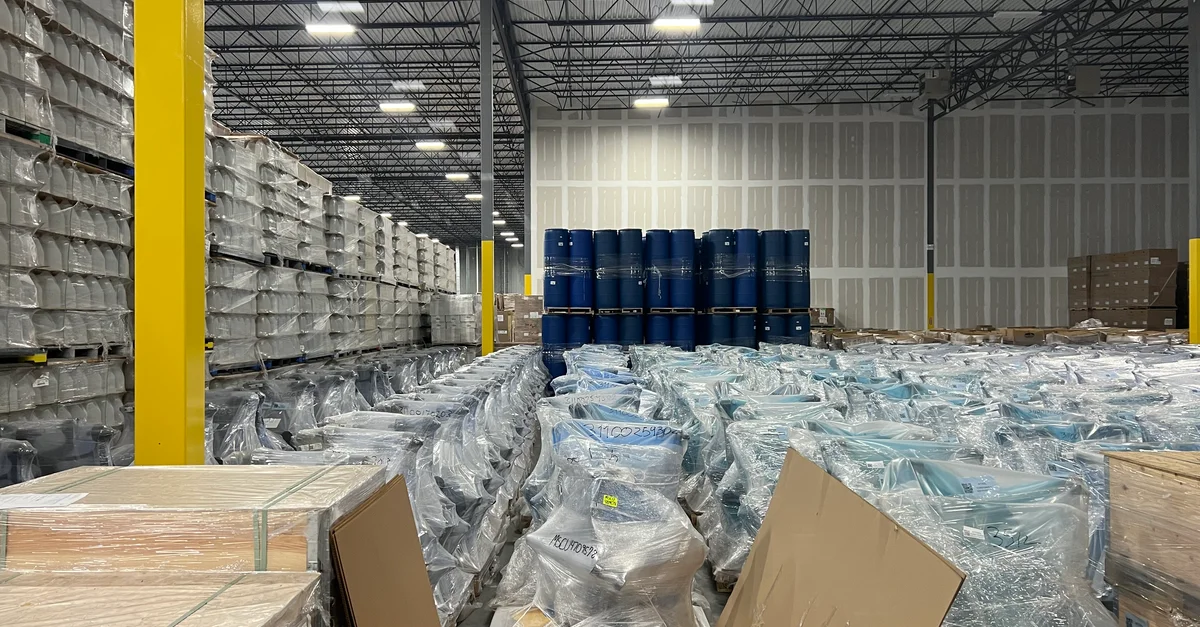 Grand entrepôt industriel rempli de marchandises empilées et emballées dans du plastique pour le stockage.