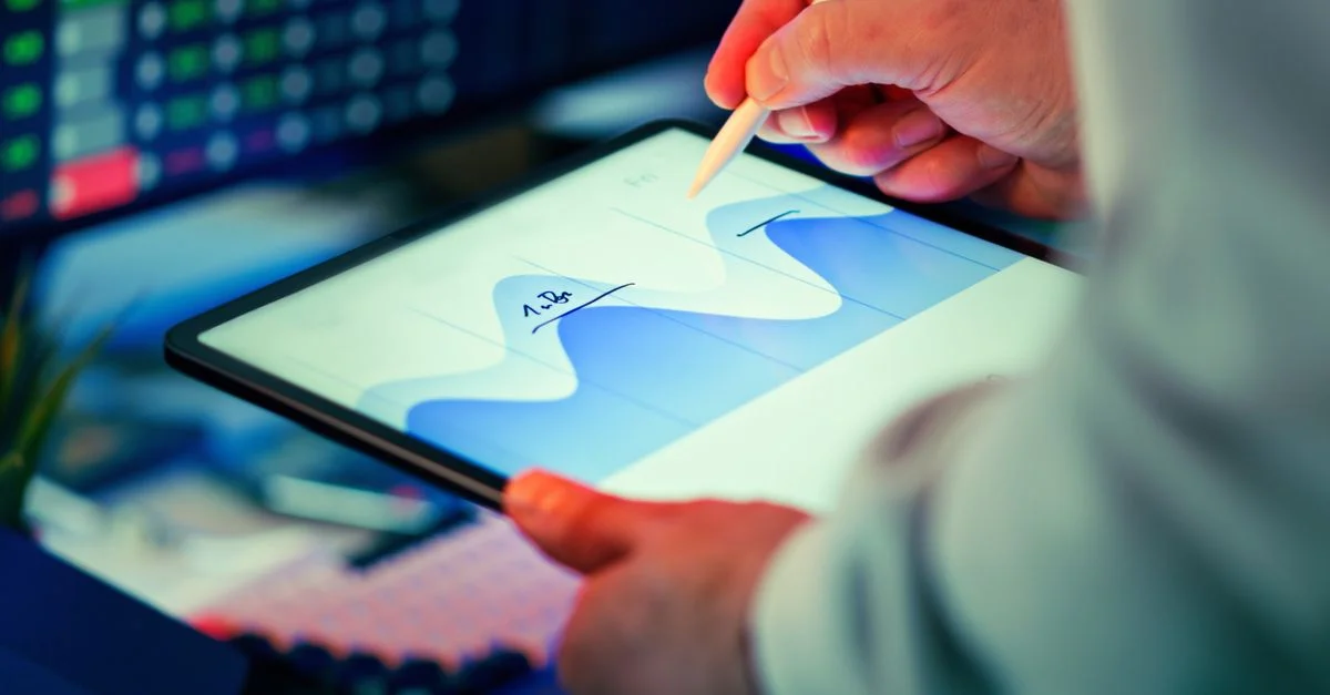 Professionnel analysant un graphique de données sur une tablette avec un stylet dans un bureau.