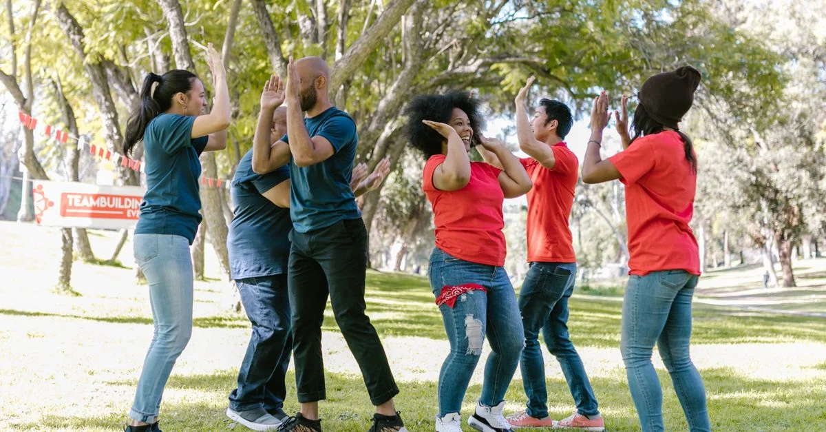 Un groupe diversifié d'adultes profitant d'une activité dynamique de renforcement d'équipe dans un parc ensoleillé.