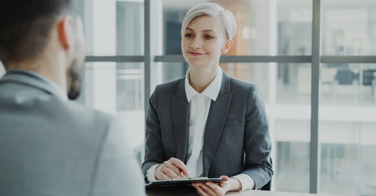 Femme confiante interviewant un candidat dans un bureau moderne. Idéal pour des visuels d'affaires et de ressources humaines.
