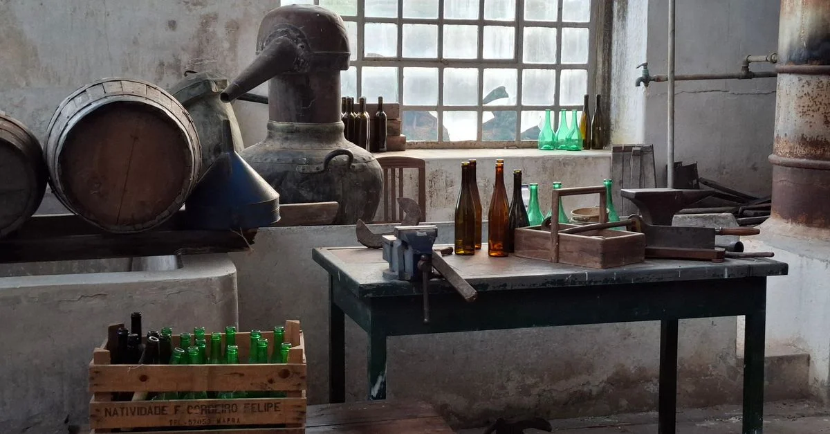 Atelier de distillerie vintage avec vieux fûts et bouteilles en verre, ambiance rustique.