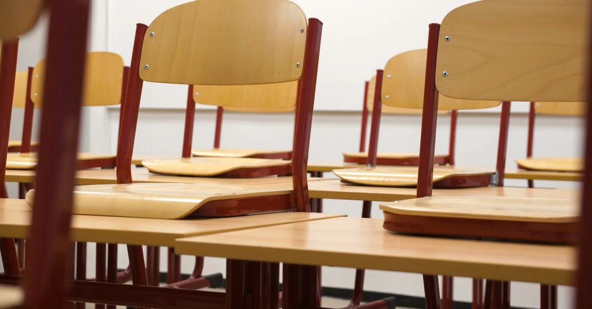 Une salle de classe moderne et vide avec des chaises et des bureaux en bois axée sur l'éducation et les espaces d'apprentissage.