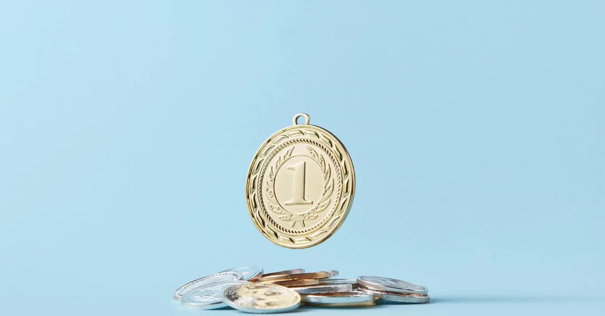 Une médaille en or et un tas de pièces sur un fond bleu clair représentant l'accomplissement et les économies.