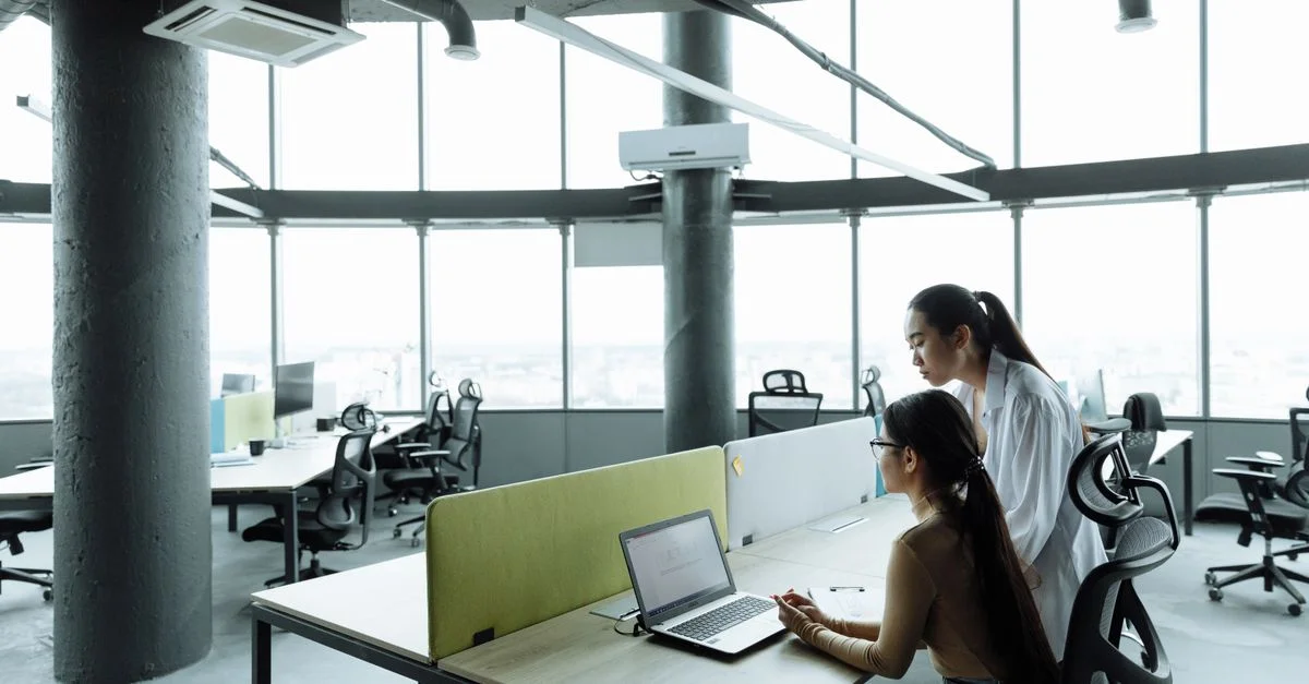 Deux femmes asiatiques collaborant dans un environnement de bureau moderne axé sur le travail d'équipe et l'innovation.