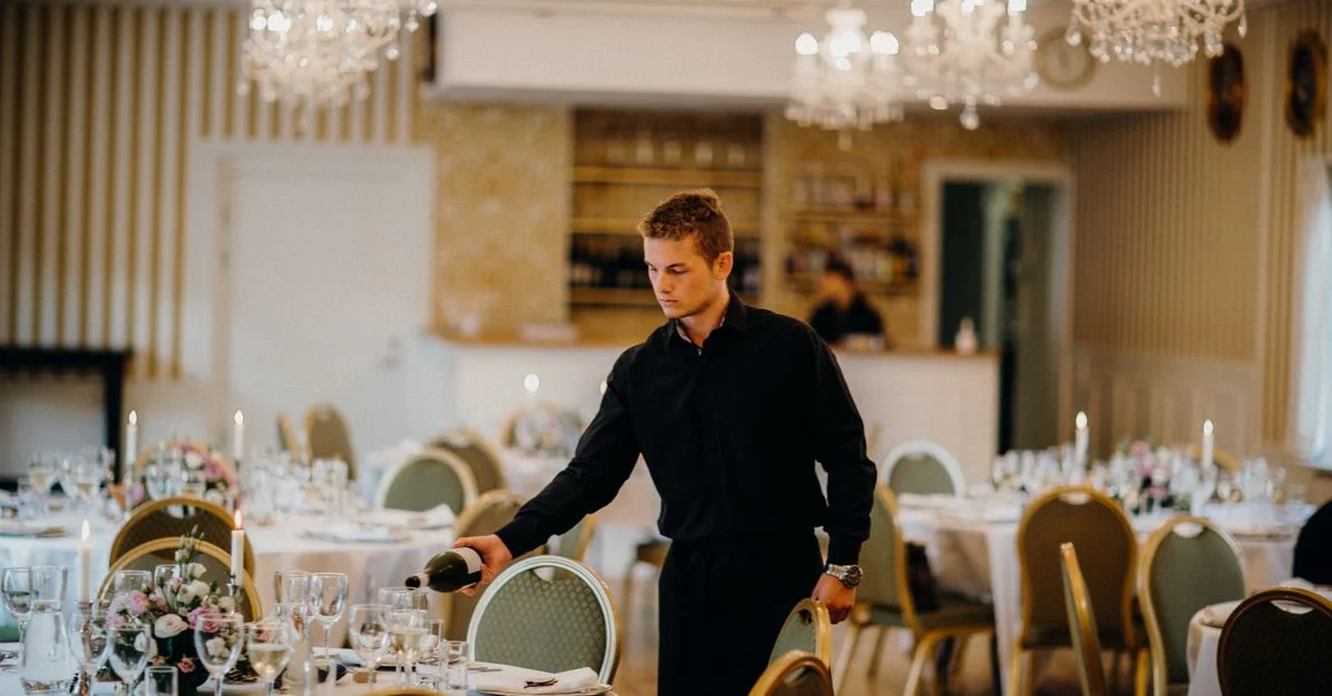 Un serveur verse du vin dans une salle à manger magnifiquement décorée, créant une ambiance élégante.